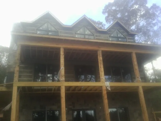 Dormers and porch framing on a large log home under construction — Roof Coating work by our crew in Cassville